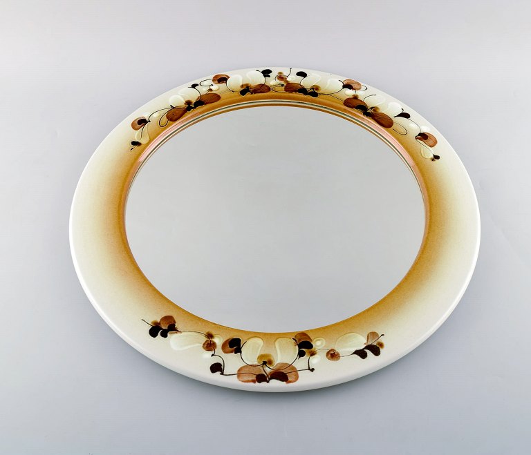 Ellen Malmer for Royal Copenhagen. Large round mirror in glazed faience decorated with flowers on the frame. Dated 1965.
