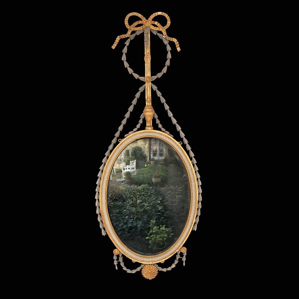 Ovalt Louis XVI spejl af "Liselund"-typen. Rigt udskåret med bl.a. guirlander og 
sløjfe. Delvist forgyldt. Danmark ca. år 1790. H: 116cm. B: 47cm