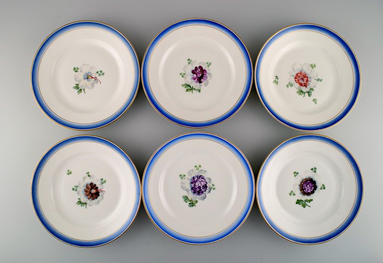 Six antique Royal Copenhagen plates in hand-painted porcelain with flowers and blue border with gold. Model number 592/9051. Late 19th century.