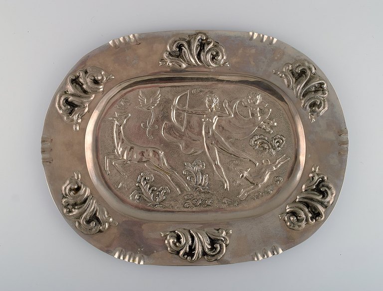 Svensk designer. Stort ovalt serveringsfad i metal med klassicistisk jagtscene. Swedish grace, 1910-1920.