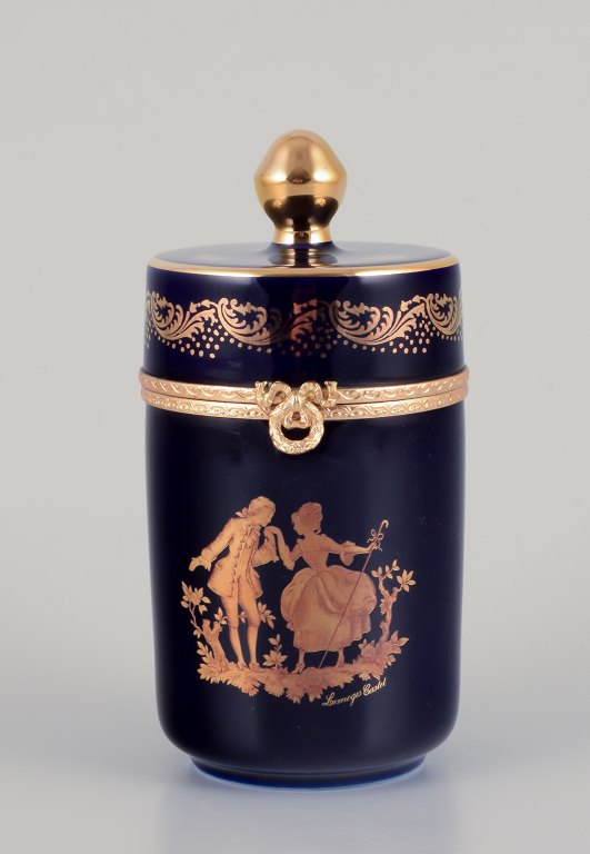 Limoges, France. Lidded porcelain box with brass mountings. Adorned with 22-karat gold leaf and featuring a beautiful royal blue glaze with a Scène galante.
