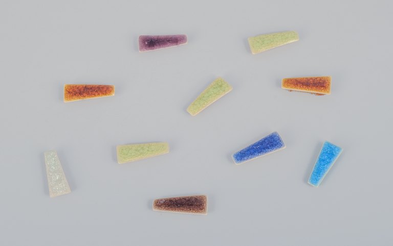 Ole Bjørn Krüger (1922-2007), dansk billedhugger og keramiker. Ti unika brocher i glaseret stentøj i forskellige farver.