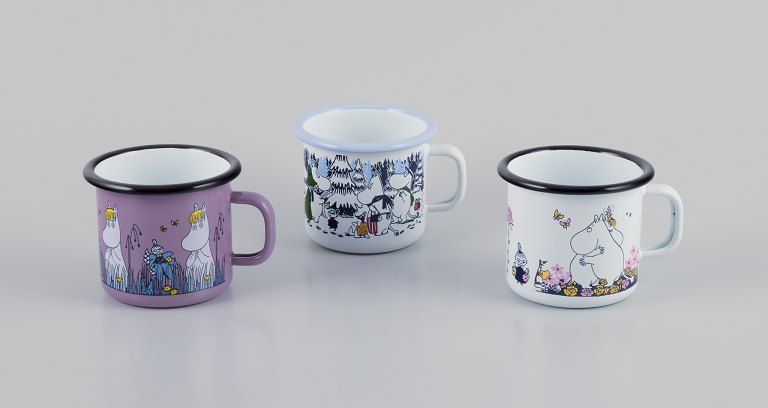 Muurla, Finland. Three enamel mugs with different motifs from the Moomin troll universe.