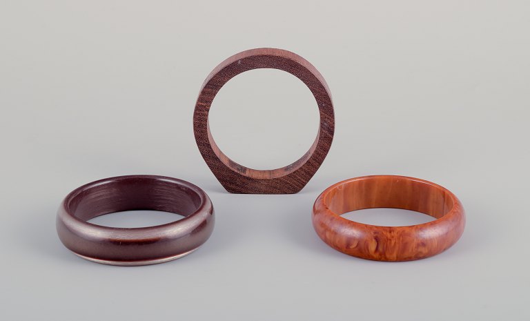 French jewelry designer.Three bracelets. Two in plastic and one in wood. Amber-colored and in shades of brown.