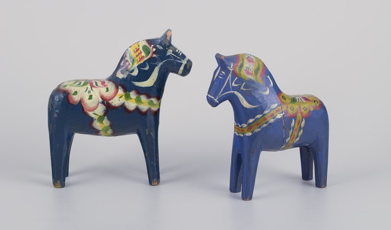 Two Dala horses. Hand-painted with floral motifs on a blue background.