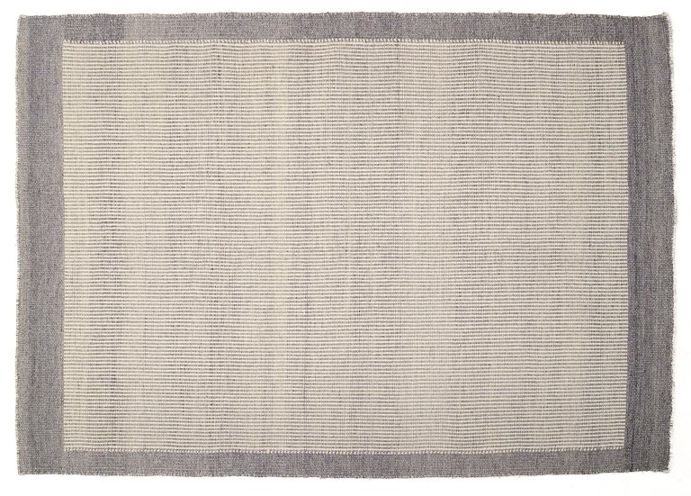 Svensk tekstildesigner.
Håndknyttet tæppe af uld. 
Vævet i grå og hvide farver.