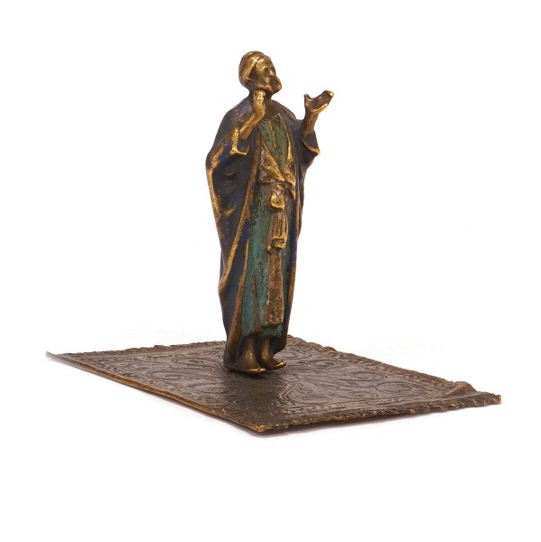 Figur forestillende orientalsk mand på tæppe i formessinget tin og dekoreret. H: 
9,5cm. Base: 9x11cm